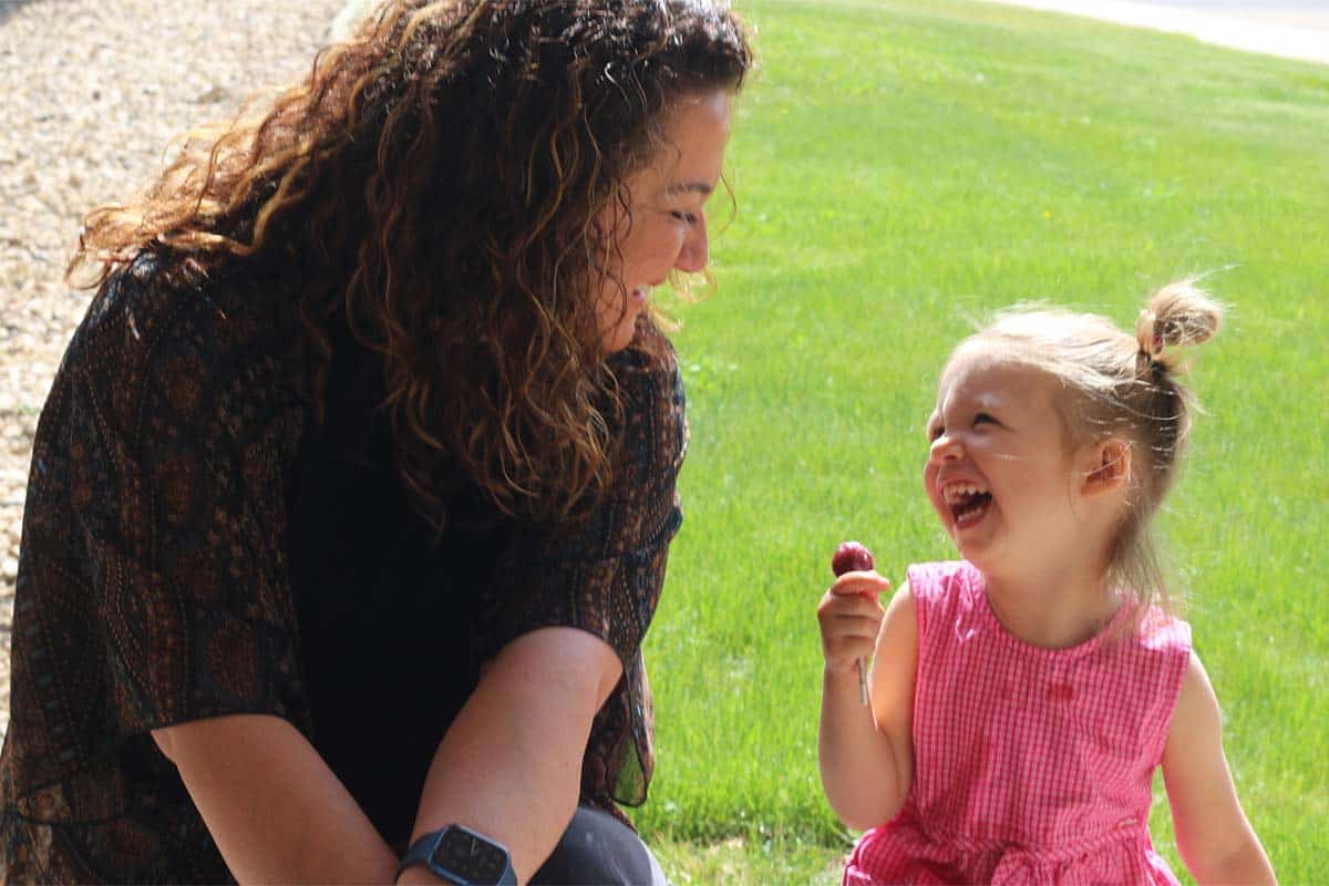 A volunteer laughing with a little girl outside the church